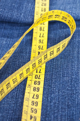 Blue jeans and measure tape - concept of overweight
