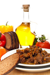 Beef goulash serving with bread and vegetables on textured table