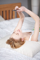 junge frau schreibt im bett eine sms
