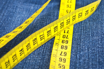 Blue jeans and measure tape - concept of overweight