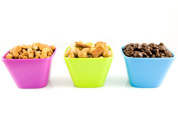 Chocolate raisins, cashew nuts and mixed nuts in colored bowls