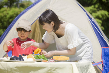 バーベキューの準備をする母親と息子 © Paylessimages