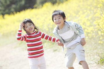Fototapeta na wymiar 菜の花畑で遊ぶ小学生男女