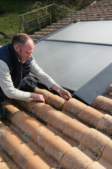 Homme posant des panneaux solaires sur la toiture d'une maison