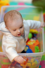 Pretty little girl sitting in a toy box