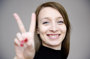 junge sympathische frau zeigt victory zeichen mit fingern