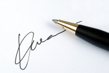Sign the name on a paper with a pen