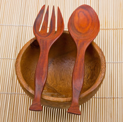 Wooden spoon, fork and basin on bamboo mat
