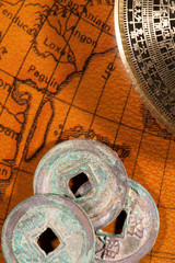 Chinese coins and compass over antique map