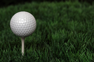 Golfball auf Tee im Gras