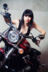 A sexy brunette woman sitting on a  motorbike