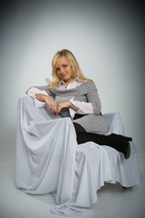 Fototapeta premium The girl young beautiful sits in an armchair sent by a white fab