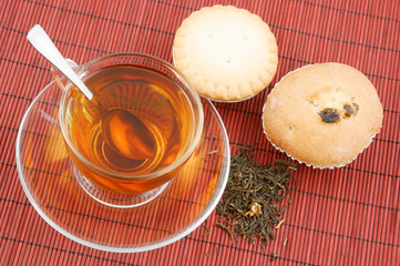 Cup of tea and two fruitcakes on bamboo background