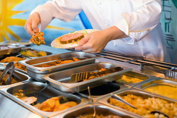 Hands of cook putting in plate vegetable ragout