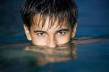 teenager boy swimming in pool at night