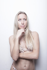 Fototapeta premium Woman posing on a white wall in a bikini