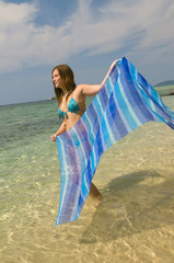 Young girl with blue sarong in hands against the see