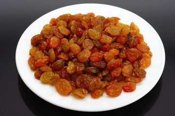 Raisin on a white plate on a black background
