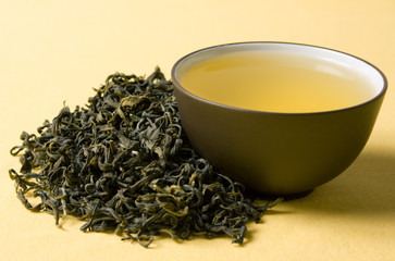 clay cup with green tea in dried tea leaves