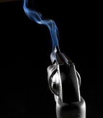 Smoking revolver on a black background just after taking a shot - obrazy, fototapety, plakaty
