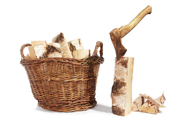 birch firewood in a wicker basket , kindling and ax