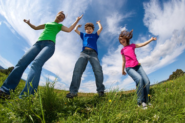 Fototapeta na wymiar Mother and kids jumping, running against blue sky