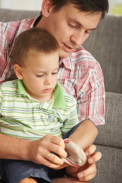 Father helping son putting on socks