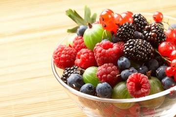 Fruit mix in the glass container, on a table from straw