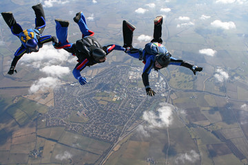 Three skydivers form a line behind each other