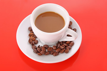 Small white cup of coffee with coffee grain  on red background