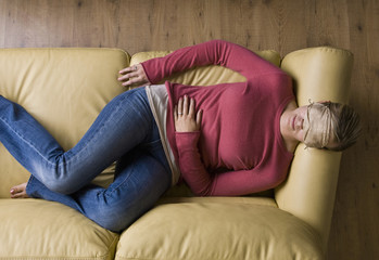 Woman laying on sofa wearing sleep mask - Powered by Adobe