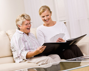 Senior woman and daughter looking at photographs