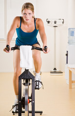 Fototapeta premium Woman riding stationary bicycle in health club