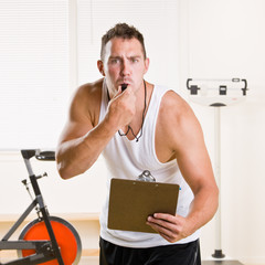 Personal trainer blowing whistle in health club