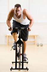 Plakat Man riding stationary bicycle in health club