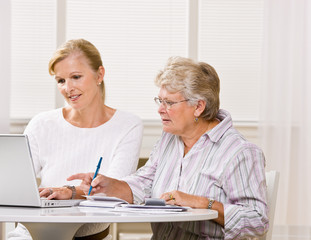 Senior woman writing checks with daughter help