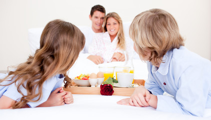 Obraz na płótnie Canvas Caucasian family having breakfast sitting on bed