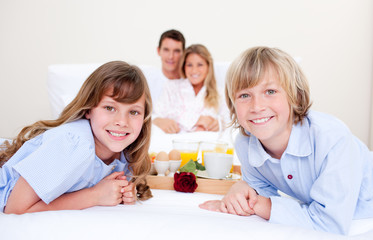 Obraz na płótnie Canvas Jolly family having breakfast sitting on bed
