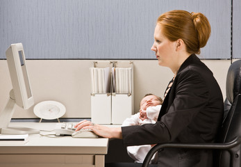 Businesswoman holding baby at desk