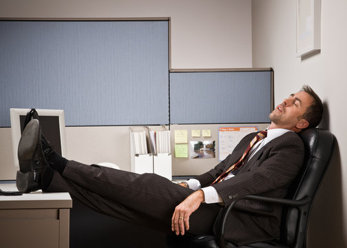 Businessman sleeping at desk with feet up