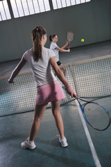 young girls playing tennis game indoor
