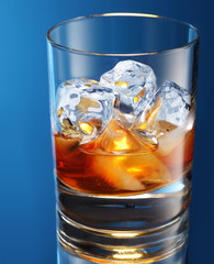 Glass of brandy with ice cubes isolated on a blue