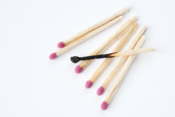 Close up of lined up matches with a burned one in the middle
