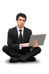 Homme d'affaire assis par terre devant ordinatuer portable