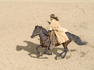 Cowboy riding a horse at full gallop with gun in hand