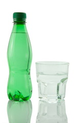 Bottle and glass of mineral water reflected on white background