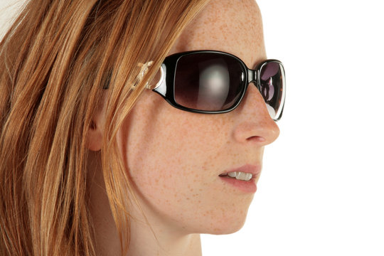 Eine rothaarige Frau mit Sonnenbrille blickt zur Seite