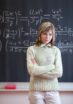 pretty college student/young teacher in front of a chalkboard in