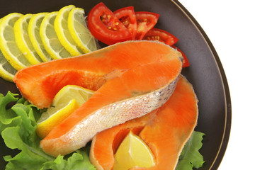 two salmon steak on dark dish