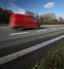 Red delivery/cargo van going fast on a highway